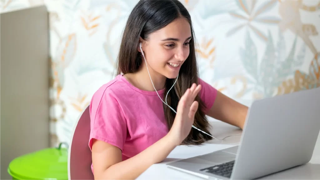 Estudiante adolescente sonriendo y saludando en una sesión de tutoría virtual